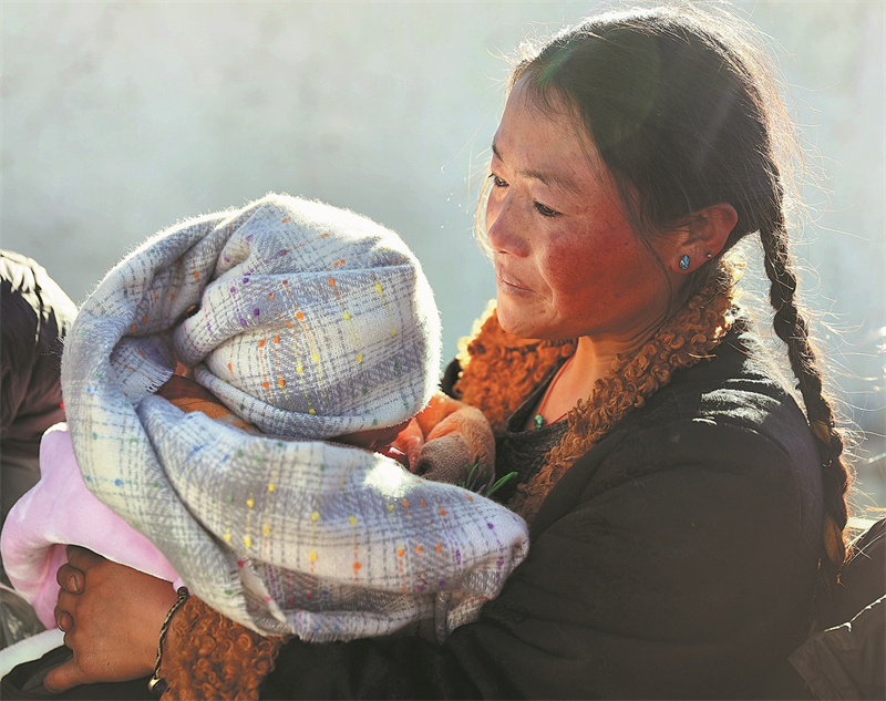 Μια γυνα?κα, κρατ?ντα? το παιδ? τη?, λαμβ?νει ζεστ? ρο?χα απ? εθελοντ?? την Τετ?ρτη 8/1/2024 στο Θ?νγκλε?, ?να χωρι? στην κοιν?τητα Δρ?μσο τη? επαρχ?α? Ντινγκρ? στο Σιγκ?τσε. Φωτογραφ?α: Xinhua