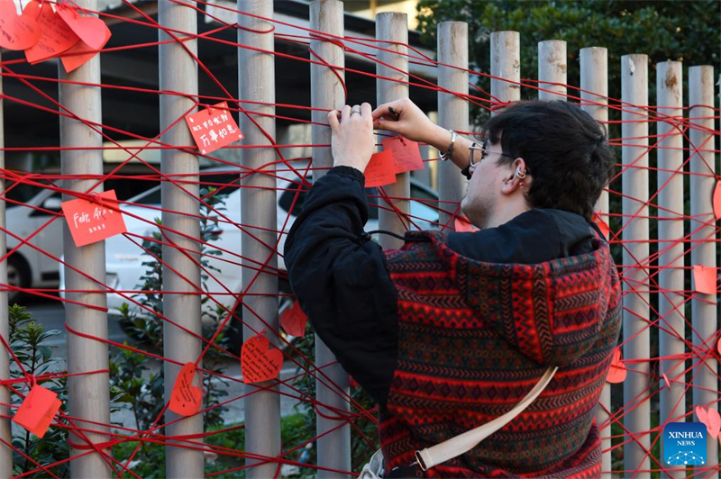 ?να? ?νδρα? τοποθετε? τι? πρωτοχρονι?τικε? ευχ?? του σε ?ναν το?χο ευχ?ν κατ? τη δι?ρκεια των εορτασμ?ν του Κινεζικο? Ν?ου ?του? στη Μαδρ?τη, Ισπαν?α, στι? 31 Ιανουαρ?ου 2025. (Φωτογραφ?α / Xinhua)