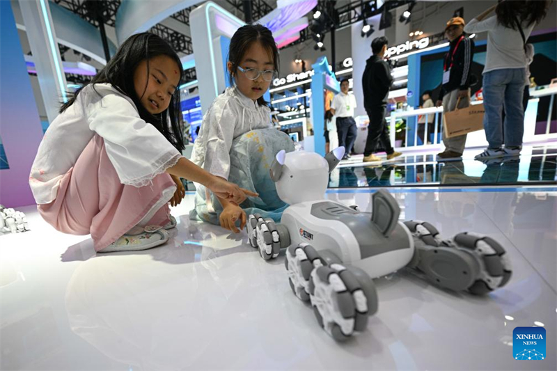 Παιδι? πα?ζουν με ?να ρομποτικ? σκυλ?κι-παιχν?δι κατ? τη δι?ρκεια τη? 5η? Διεθνο?? ?κθεση? Καταναλωτικ?ν Προ??ντων τη? Κ?να? (CICPE) στο Χα?κο?, στην επαρχ?α Χα?ν?ν, στη ν?τια Κ?να, στι? 13 Απριλ?ου 2025. (Φωτογραφ?α / Xinhua)