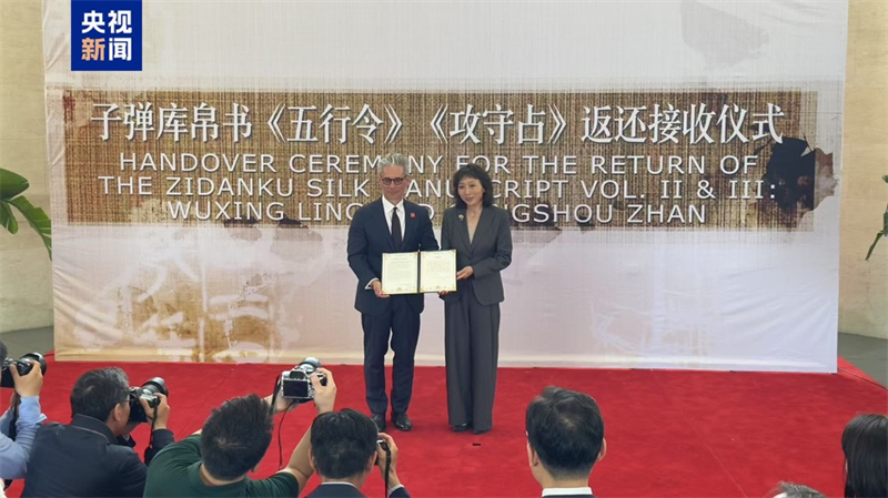 Η Τζου Γι? (δεξι?), αναπληρ?τρια γενικ? διευθ?ντρια του Γραφε?ου για την Αν?κτηση και Αποκατ?σταση Χαμ?νων Πολιτιστικ?ν Αγαθ?ν, τη? Εθνικ?? Διο?κηση? Πολιτιστικ?? Κληρονομι?? τη? Κ?να?, λαμβ?νει πιστοποιητικ? μεταβ?βαση? απ? τον Τσ?ι? Φ. Ρ?μπινσον, διευθυντ? του Εθνικο? Μουσε?ου Ασιατικ?? Τ?χνη? του Σμιθσ?νιαν, κατ? τη δι?ρκεια τελετ?? παρ?δοση? των αρχα?ων Χειρογρ?φων Μεταξιο? Τζιντανκο? απ? την περ?οδο των Εμπ?λεμων Κρατ?ν στην Κινεζικ? Πρεσβε?α στι? Ηνωμ?νε? Πολιτε?ε? στην Ου?σινγκτον, στι? 16 Μα?ου 2025. /CMG